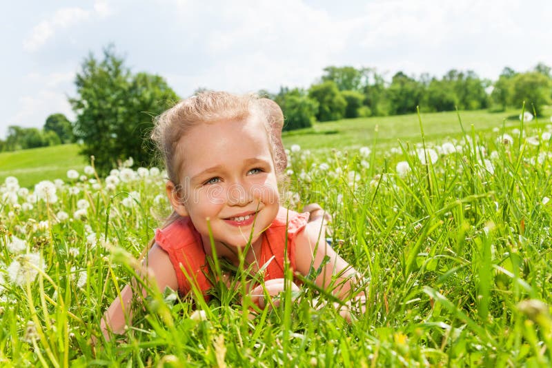 Young smiling girl in red laying on the grass on a sunny day. Young smiling girl in red laying on the grass on a sunny day.