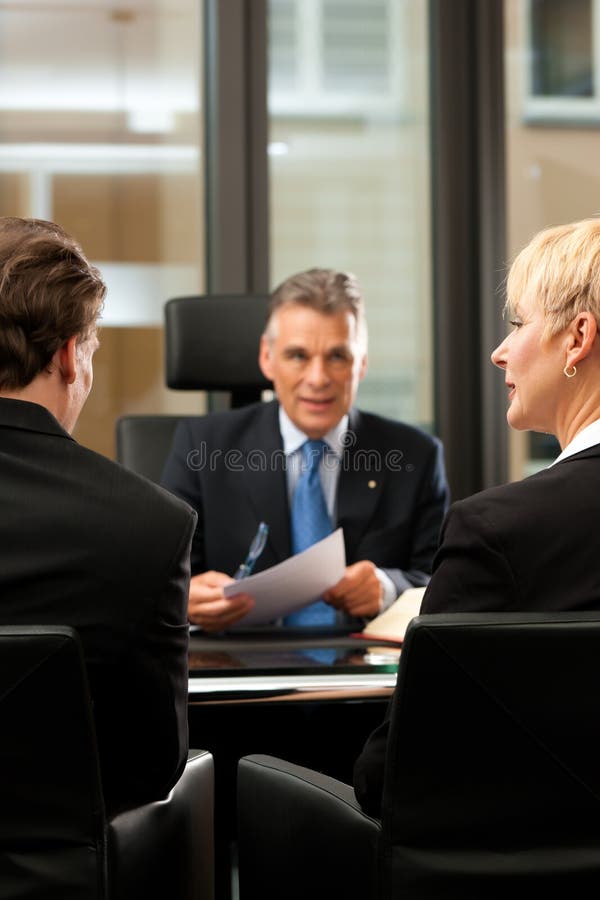 Mature lawyer or notary with clients in his office in a meeting. Mature lawyer or notary with clients in his office in a meeting