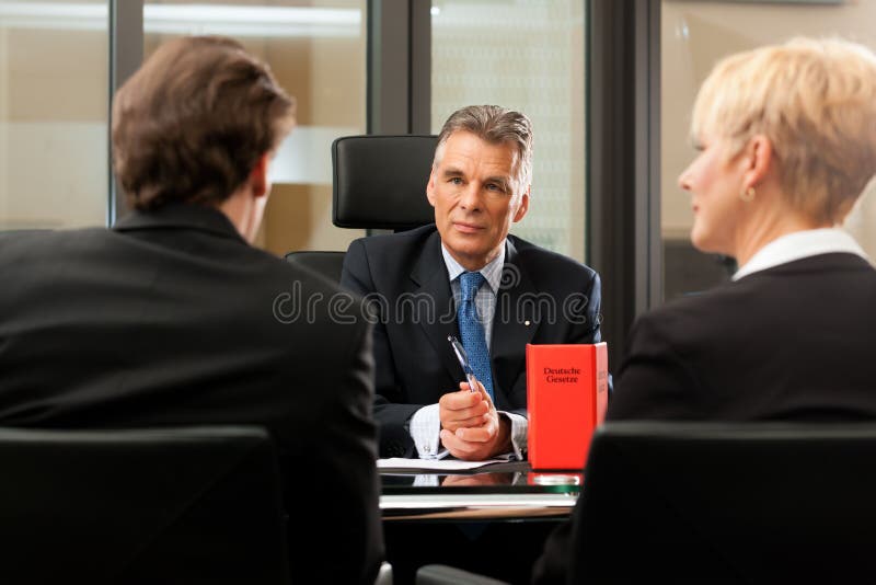 Mature lawyer or notary with clients in his office in a meeting. Mature lawyer or notary with clients in his office in a meeting