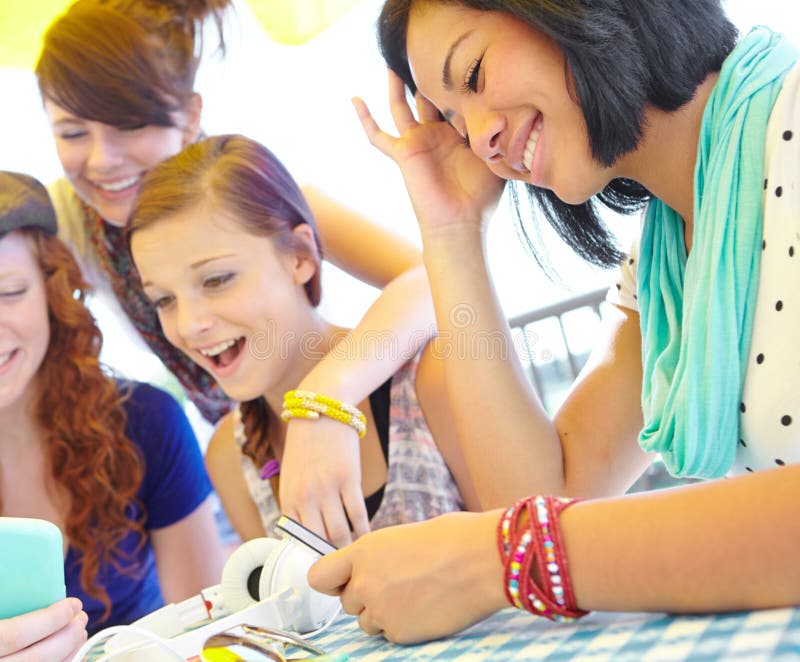 Receiving a sweet text. A group of adolescent girls laughing as they look at something on a smartphone screen. Receiving a sweet text. A group of adolescent girls laughing as they look at something on a smartphone screen