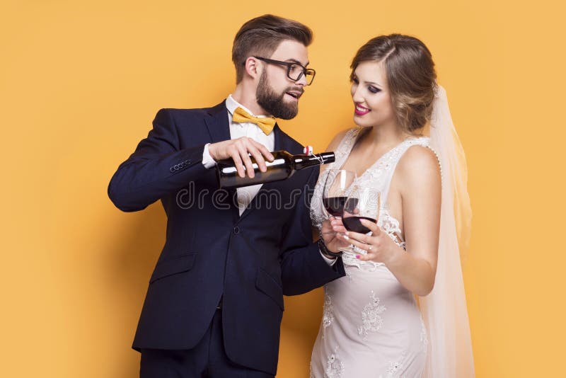 Recienes casados que celebran el vino rojo de consumición imagen de archivo Recienes casados que celebran el vino rojo de consumición imagen de archivo