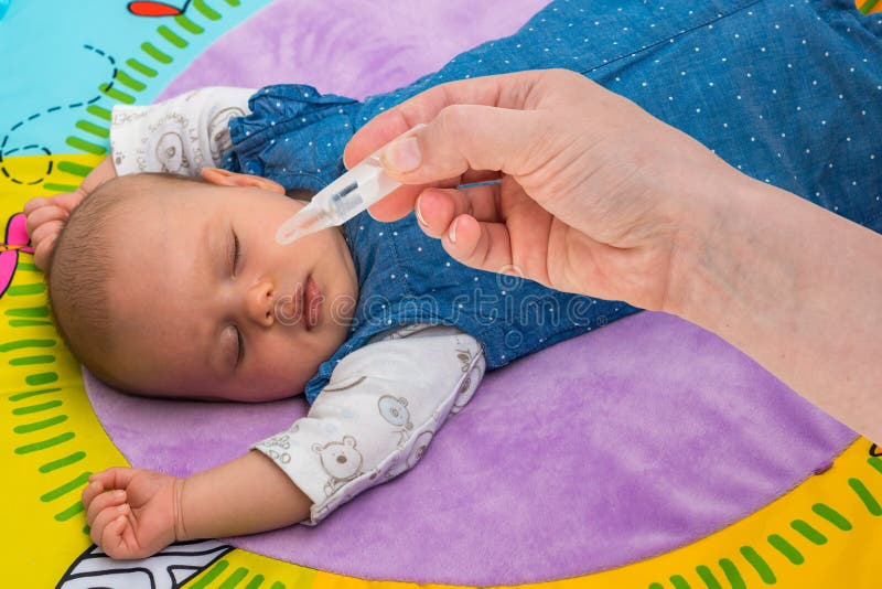 Newborn gets nose drops with saline solution in morning. Newborn gets nose drops with saline solution in morning