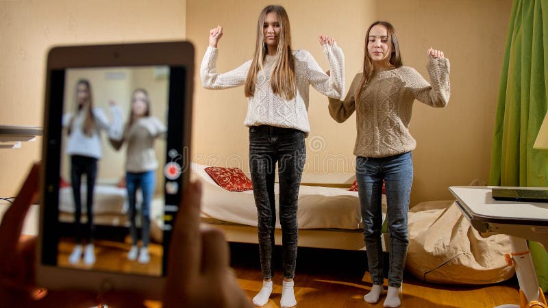 REcording video on smartphone of two teenage girls dancing for posting in internet. Modern communication, social media