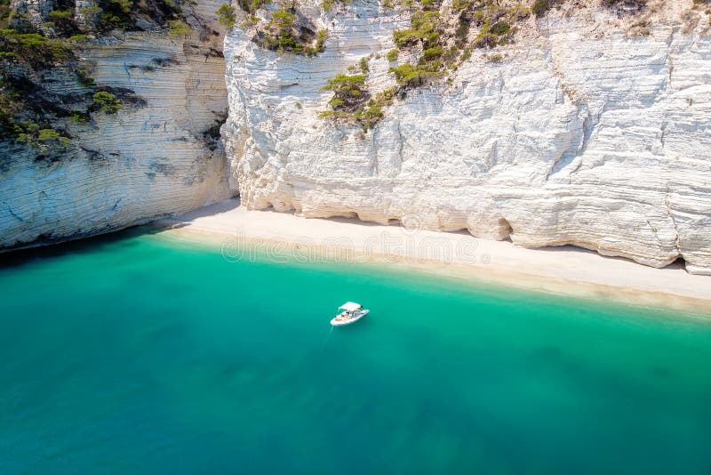 Recreation small boat in beautiful gulf with turquoise water. Faraglioni sea stacks in Puglia, Baia delle Zagare stock images Recreation small boat in beautiful gulf with turquoise water. Faraglioni sea stacks in Puglia, Baia delle Zagare stock images