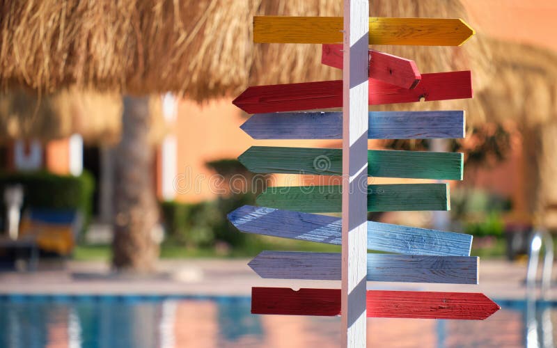 Recreere de vară în țări tropicale. panou colorat care indică direcția spre exterior a umbrelor de paie pentru paie din bazinul ex stock image