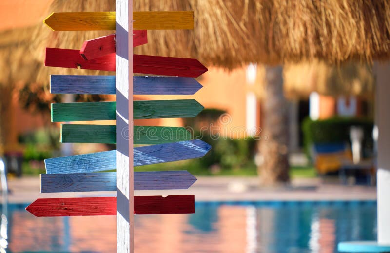 Recreere de vară în țări tropicale. panouri colorate care indică direcția spre exterior a umbrelor de paie din paie de la piscina stock photos