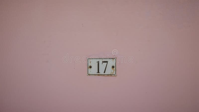 Weathered House Number \'17\' Sign on Pastel Pink Wall royalty free illustration