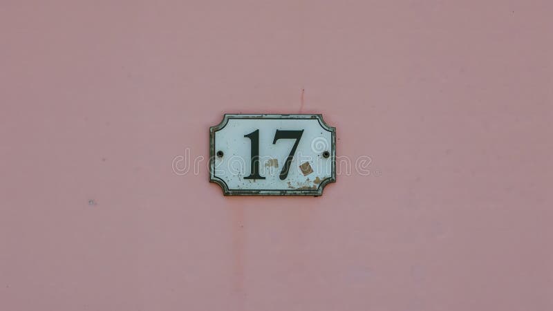 Weathered House Number \'17\' Sign on Pastel Pink Wall royalty free illustration