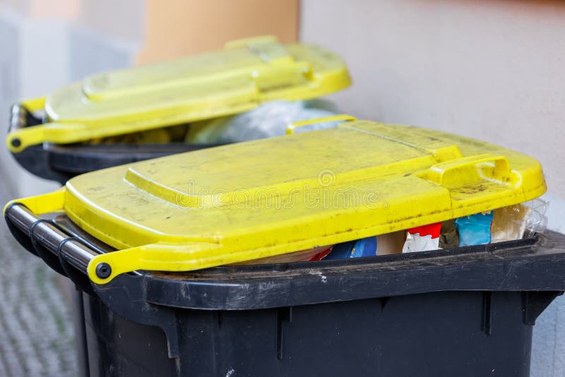 Recyclage complet poubelles en plastique jaune avec couvercles jaunes dans un contexte urbain signalant la gestion des déchets images libres de droits