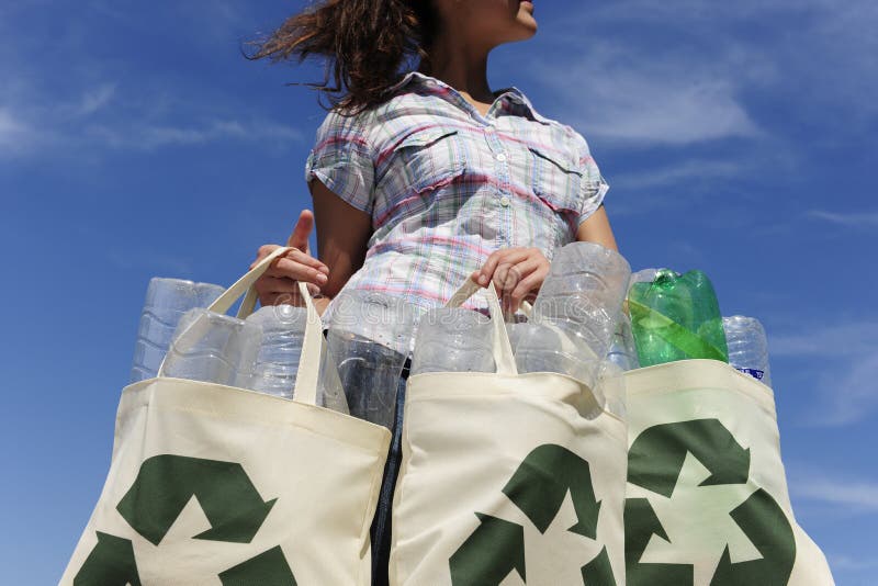 Riciclaggio donna in possesso di sacchetto con le bottiglie di plastica contro il cielo blu.