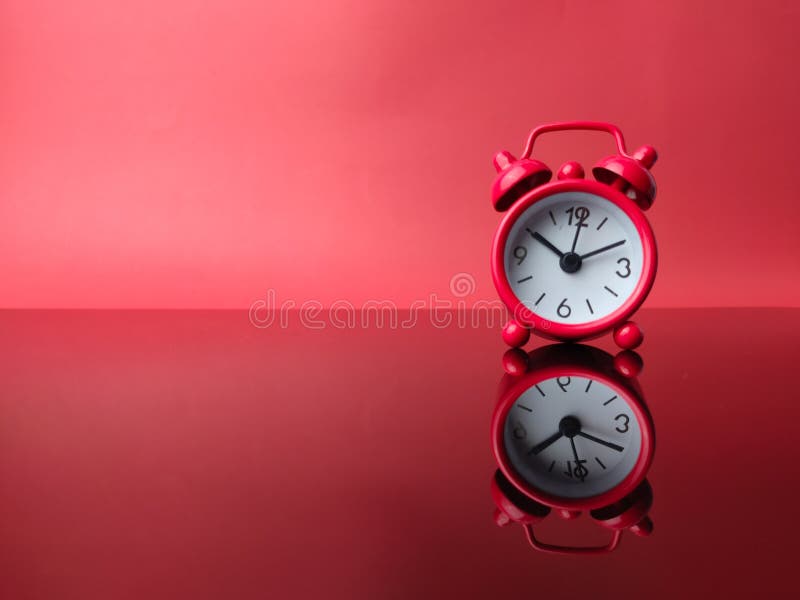 Red alarm clock with reflection on a red background stock photo