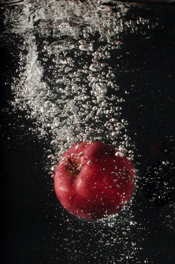 Red apple falling into water