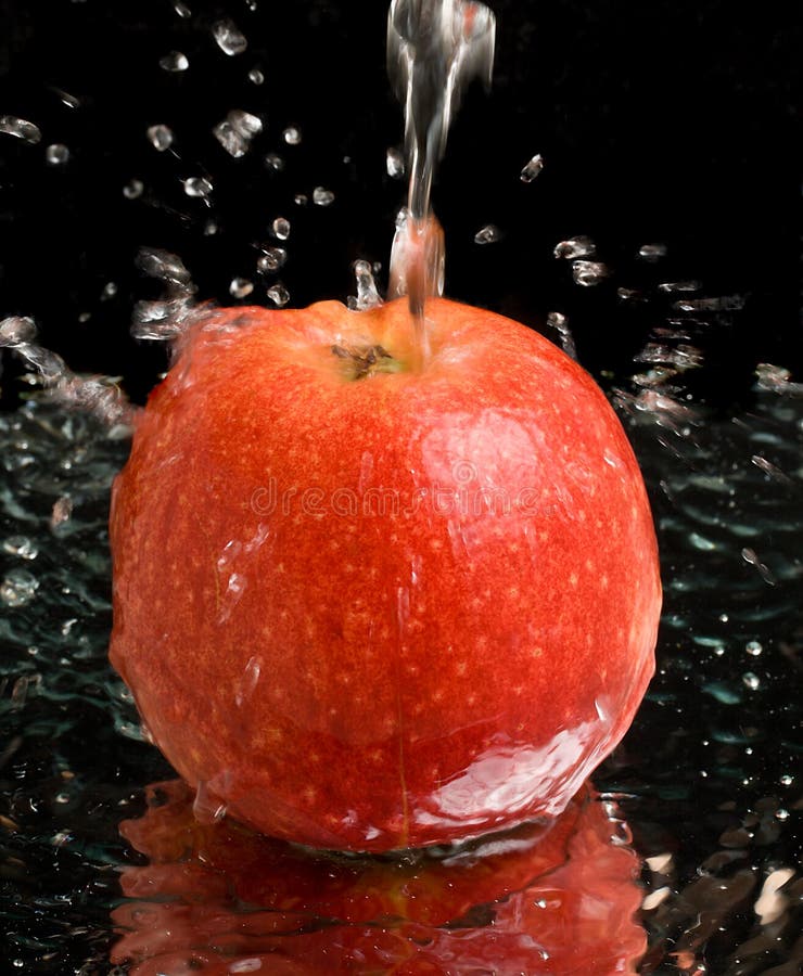 Red apple under water stream with splashes