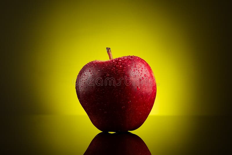 Red apple with water drops on yellow background