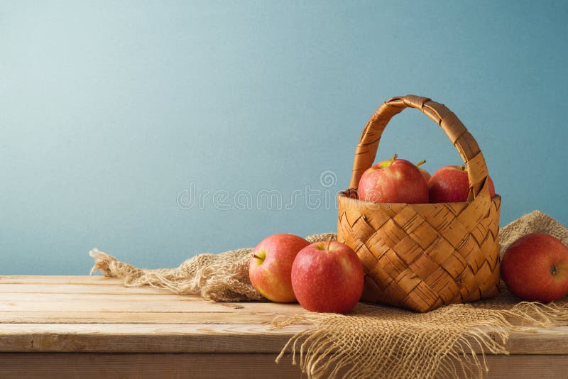 Red apples in basket on wooden kitchen table background