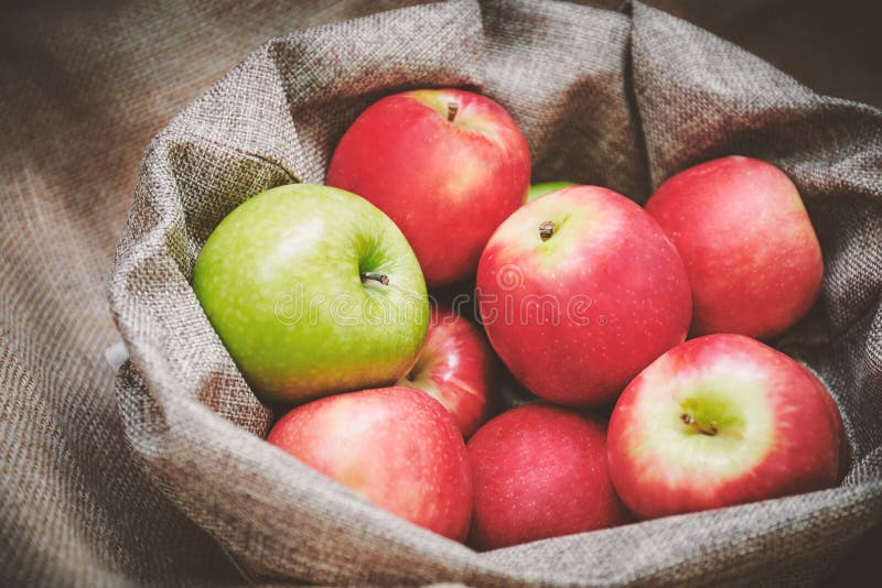 Red apples, green apple in the bowl cover with burlap, top view royalty free stock photos