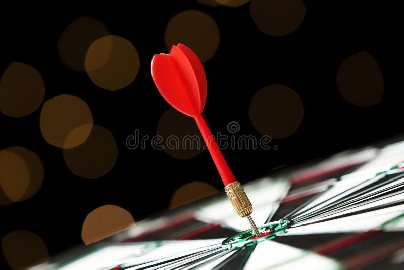 Red arrow hitting target on dart board against blurred