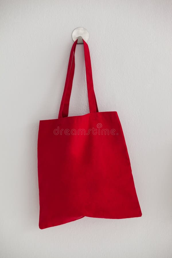 Red fabric bag hanging on self adhesive hook on white wall. Red fabric bag hanging on self adhesive hook on white wall