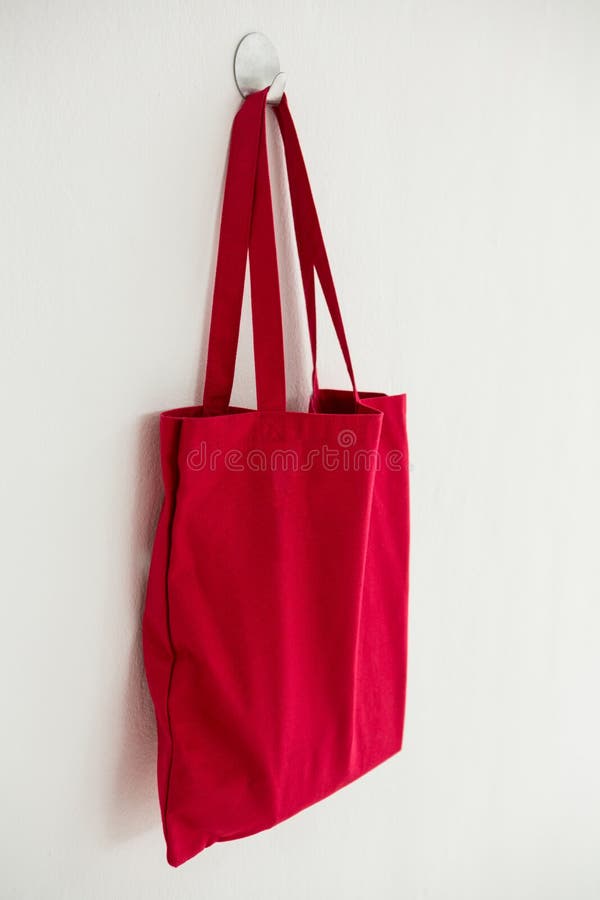 Red fabric bag hanging on self adhesive hook on white wall. Red fabric bag hanging on self adhesive hook on white wall