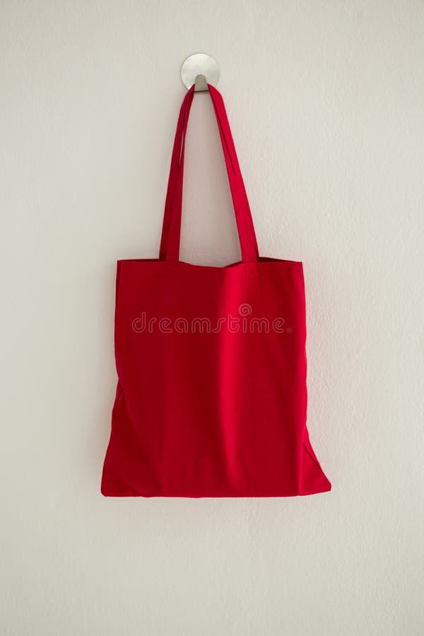 Red fabric bag hanging on self adhesive hook on white wall. Red fabric bag hanging on self adhesive hook on white wall