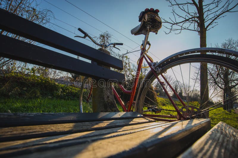 Red bicycle resting on a bench