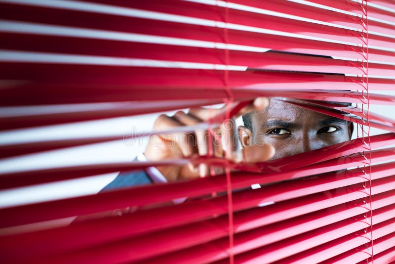 Afro-americký podnikateľ, pozrel sa cez červené žalúzie.