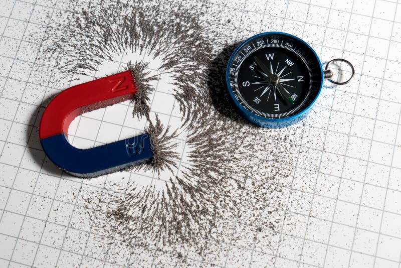 Red and blue horseshoe magnet or physics magnetic and compass with iron powder magnetic field on white paper graph background. Scientific experiment in science royalty free stock photography Red and blue horseshoe magnet or physics magnetic and compass with iron powder magnetic field on white paper graph background. Scientific experiment in science royalty free stock photography