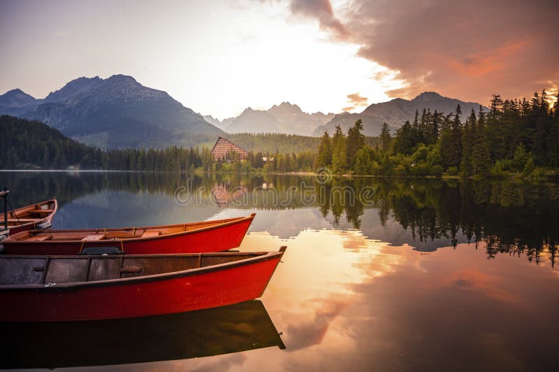 Red boats on Lake Strbske pleso. Morning view of the High Tatras National Park, Slovakia, Europe.