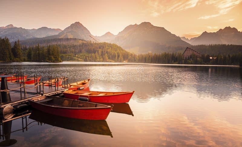 Red boats on Lake Strbske pleso. Morning view of the High Tatras National Park, Slovakia, Europe.