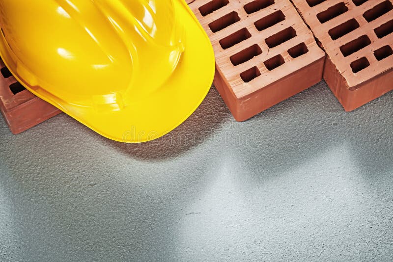 Red building bricks safety hard hat on concrete background const