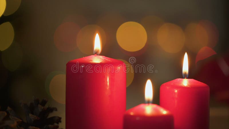 Red candles burning, Christmas lights twinkling on background, miraculous time