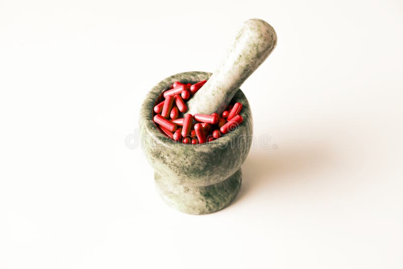 Red capsules and orange pills with mortar pestles on white background.