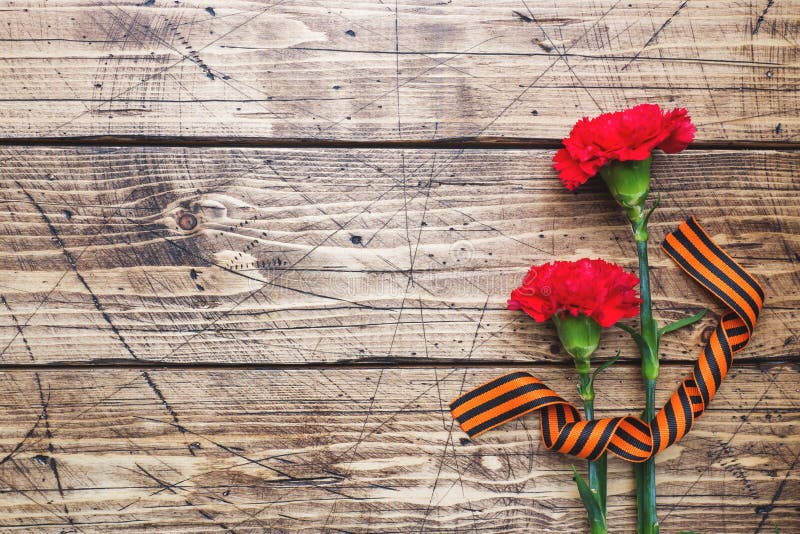 Red carnations and St. George ribbon on wooden background. Symbol may 9, victory day Copy space stock photography Red carnations and St. George ribbon on wooden background. Symbol may 9, victory day Copy space stock photography