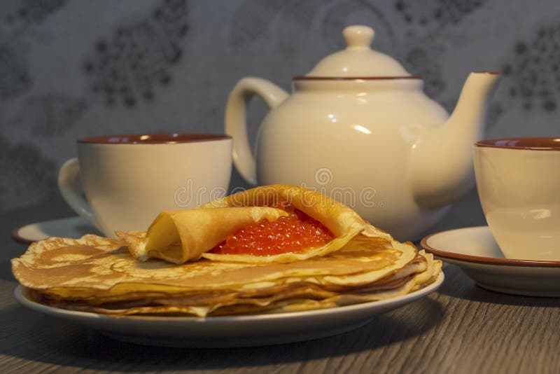 Red caviar and pancakes on the background of the teapot stock photography