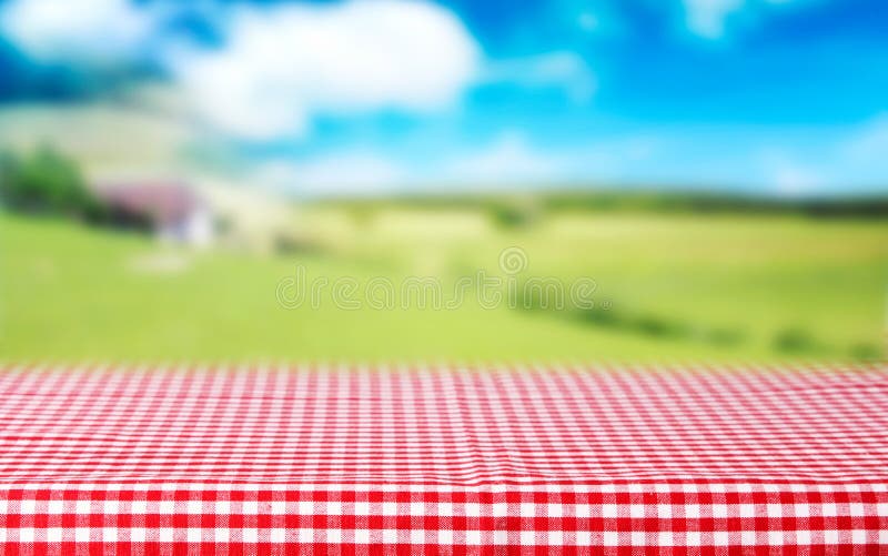 Red checkered tablecloth top view green nature blurred background.