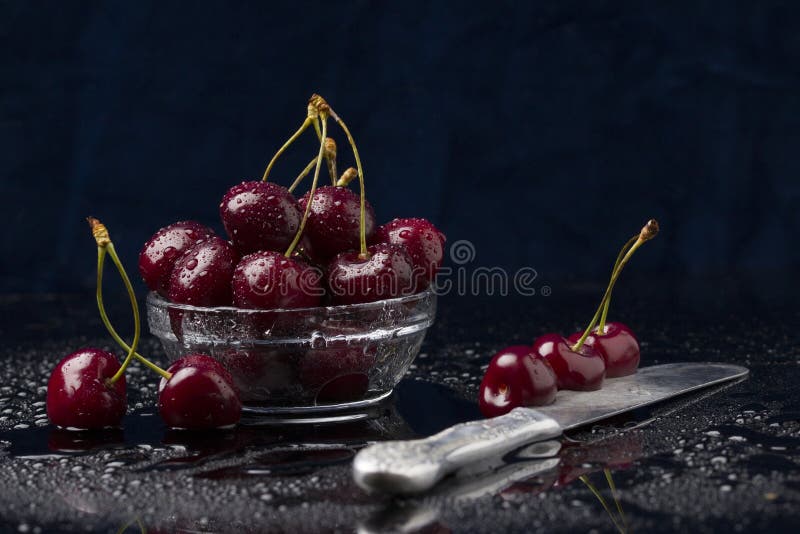 Red cherries on dark background. Heap of juicy wet cherries. Close-up view of ripe organic cherries with water drops on black .