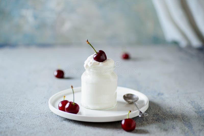 Red cherries dipped in whipped cream or yoghurt royalty free stock image