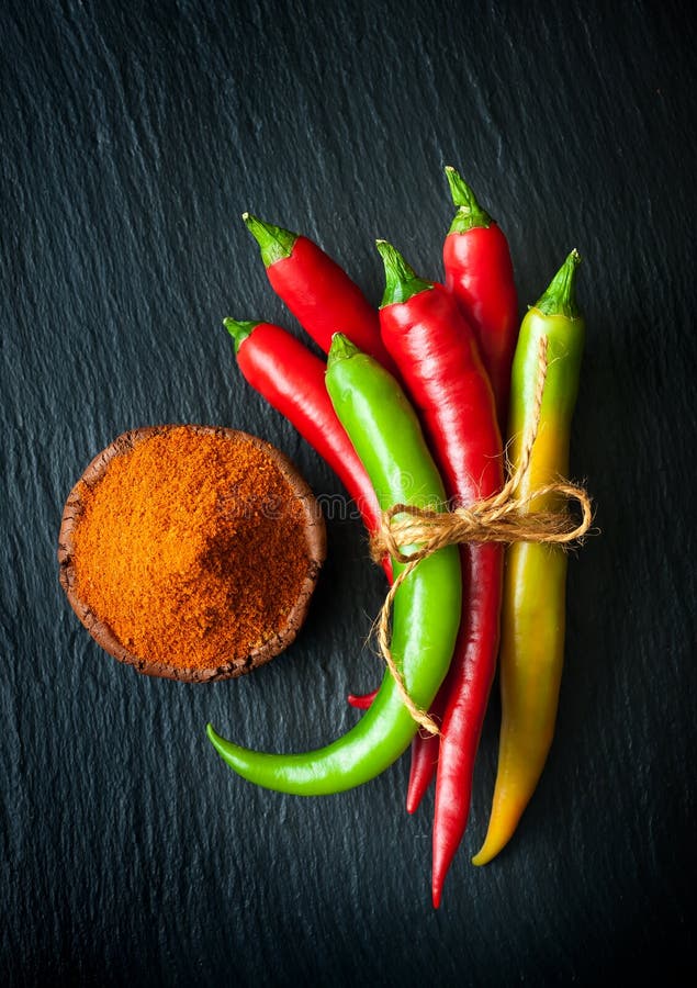 Red chili peppers and green chili peppers on a slate chalkboard