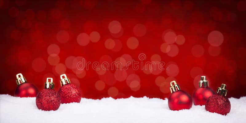 Red Christmas baubles on snow with a red background