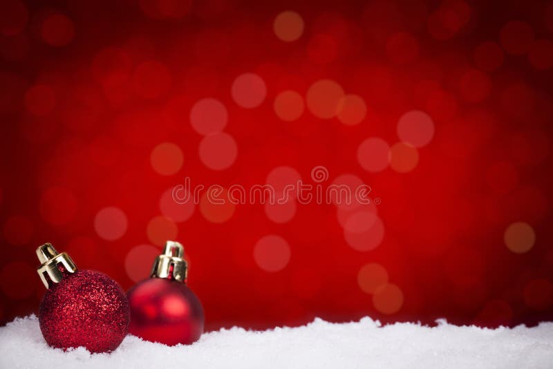 Red Christmas baubles on snow with a red background