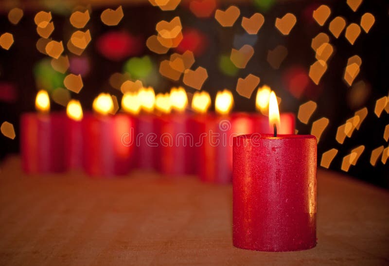 Red Christmas candle burning on a wooden table