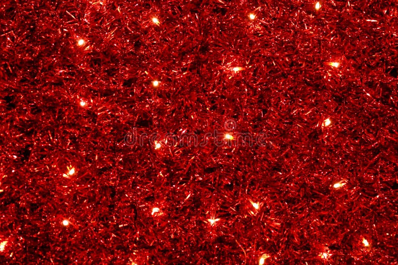 Red Christmas festive decorative background with tinsel, flashing lights. Wall illuminated by Christmas string rice lights bulbs. New Year lighting decoration in red and yellow color.