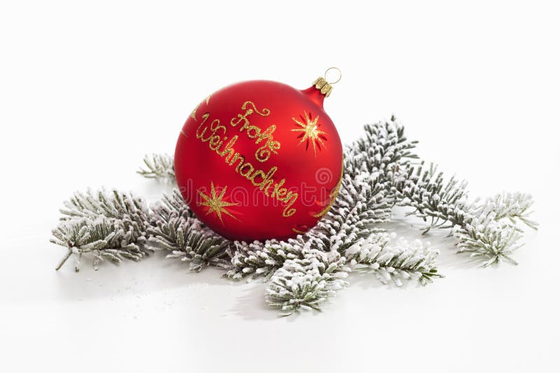 Red christmas sphere with golden writing on it on pine twig