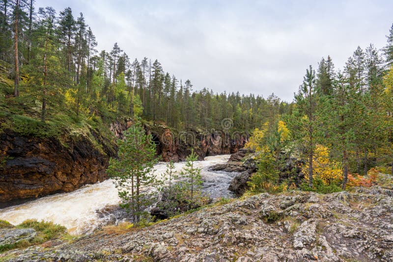 Red cliff, stone wall, forest, waterfall and wild river view in autumn