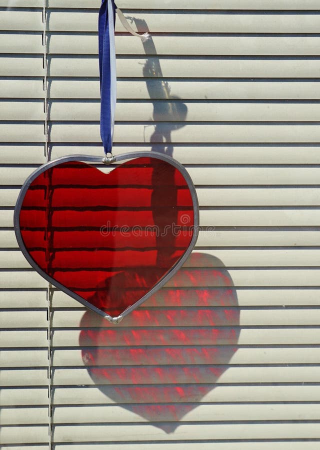 Red Cut Glass Heart Reflection in a Window with Blinds