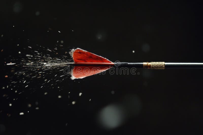 A red dart hits the center of a target on a black background stock photos