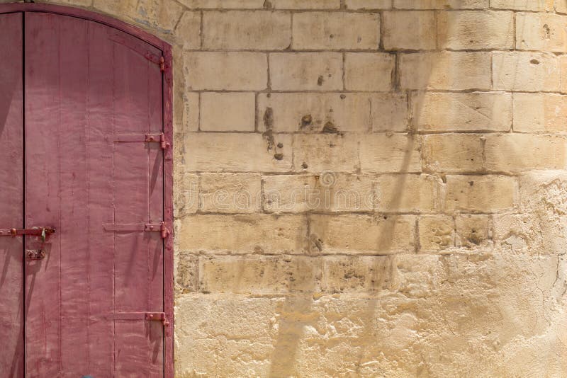 Red double door in yellow limestone wall