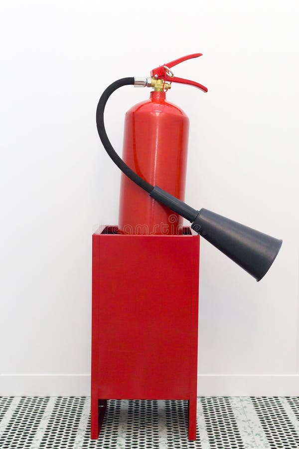 Red Fire Extinguisher Stands on the Floor in a Box on a White