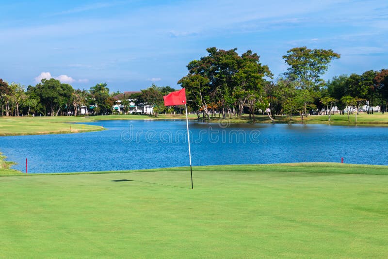 Red flag and sand bunker at the beautiful golf course at the lake side at sunset stock images Red flag and sand bunker at the beautiful golf course at the lake side at sunset stock images
