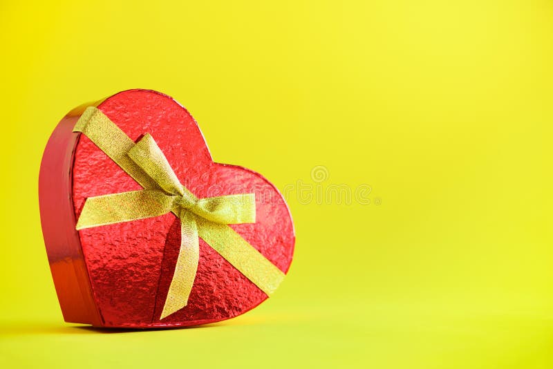 Red gift box in shape of heart on yellow background. Copyspace for text. Valentines day. Romantic love concept. Present for her stock image